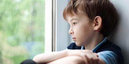 Sad child looking out a window