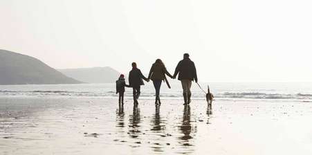 Family walking along a beach at sunset
