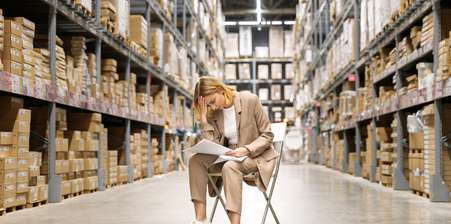 a worried woman sitting an empty warehouse , looking down at papers in her hands