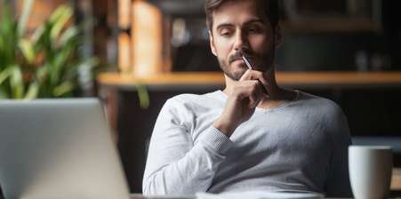 Man sitting behind laptop, looking thoughtfull