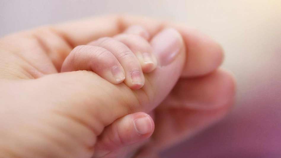 Babies hand wrapped around a mothers thumb
