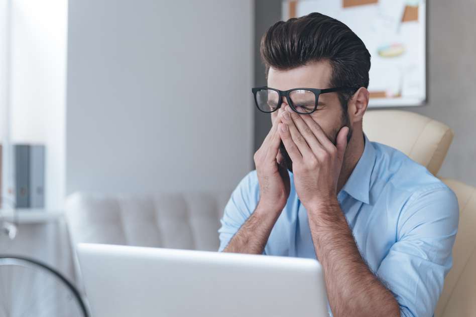 man looking exhausted in front of a computer