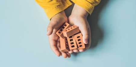Two hands holding small bricks