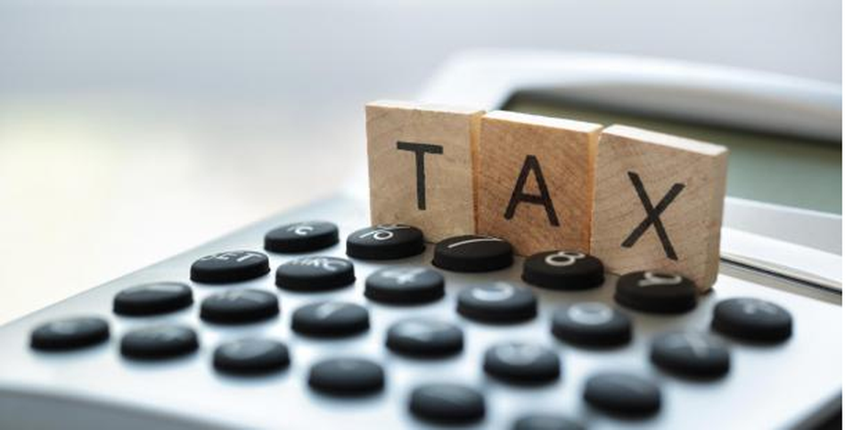 The word "tax" written using scrabble pieces on a calculator -captital gains tax on property article