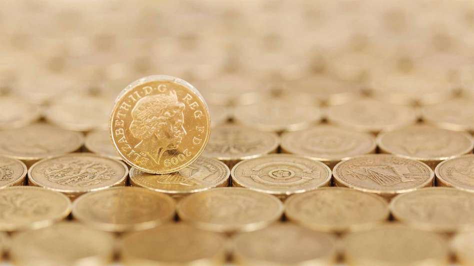 A pound coin rolling upon a bed of pound coins