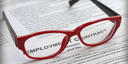 Red pair of glasses on top of an employment contract - negotiating settlement agreement solicitor
