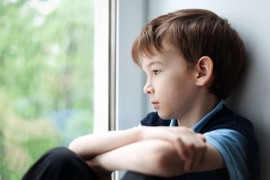 Sad child looking out a window