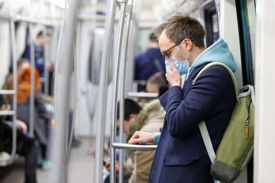 Man covering mouth on a train because of the Coronavirus