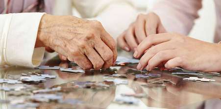 An elderly and young woman playing with a jigsaw