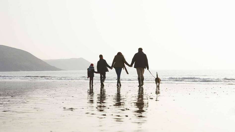 Family walking along a beach at sunset