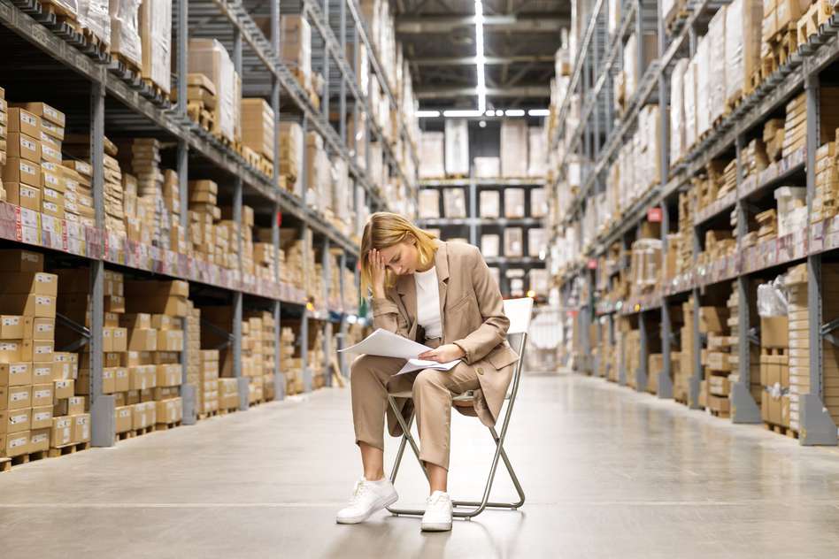 a worried woman sitting an empty warehouse , looking down at papers in her hands