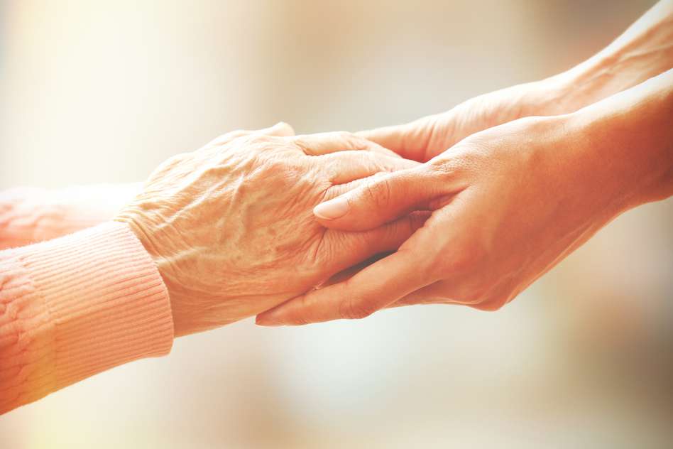 Older person hands holding a younger person's hands