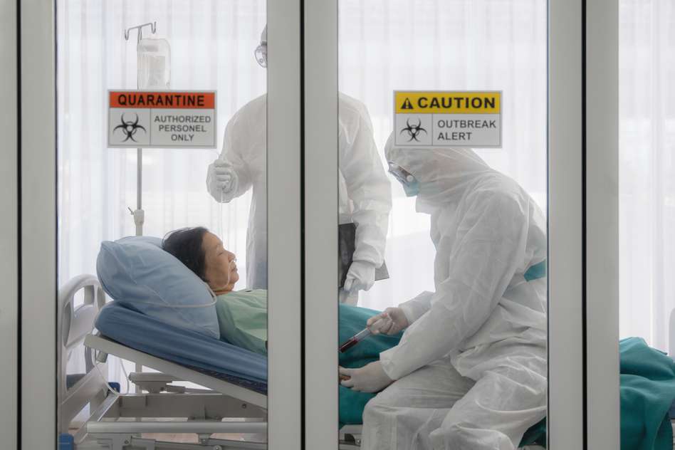 Hazmat wearing doctors besides a patient