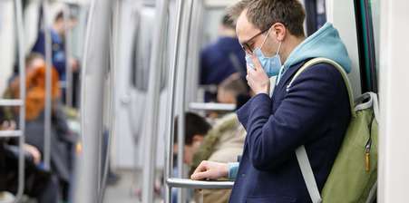 Man covering mouth on a train because of the Coronavirus