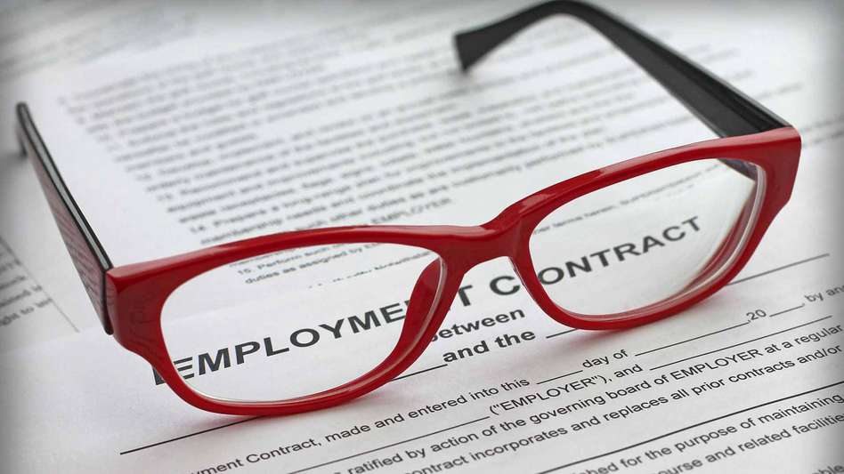 Red pair of glasses on top of an employment contract - negotiating settlement agreement solicitor