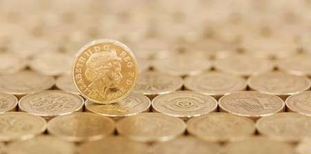 A pound coin rolling upon a bed of pound coins