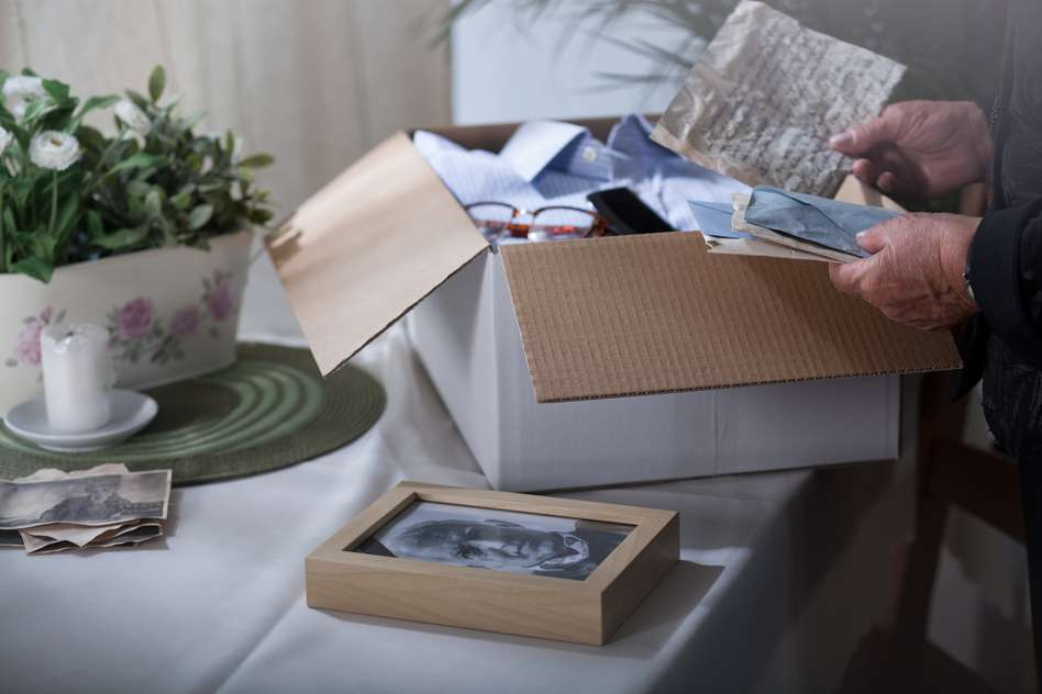 Someone packing a loved one's pictures and valuables after their death